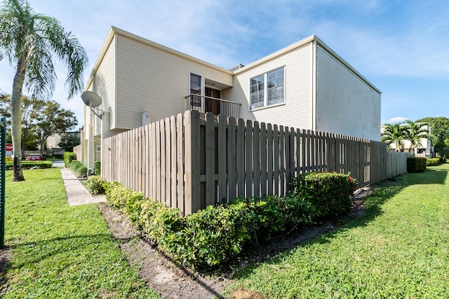 view of side of property with a lawn and a balcony