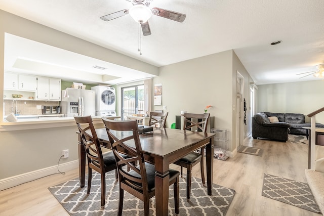 dining space featuring ceiling fan, light hardwood / wood-style flooring, stacked washing maching and dryer, and a textured ceiling