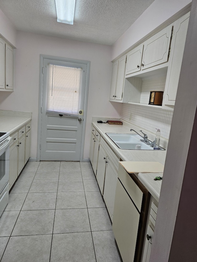 kitchen featuring sink, a textured ceiling, tasteful backsplash, light tile patterned flooring, and white cabinetry