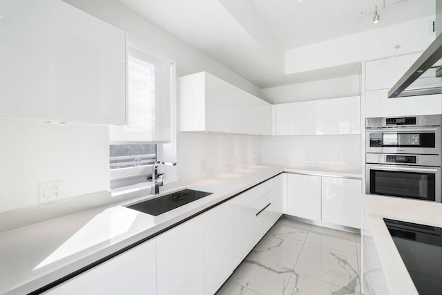 kitchen featuring double oven, white cabinetry, and sink