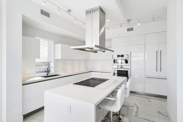 kitchen featuring black electric stovetop, sink, double oven, a kitchen island, and island exhaust hood