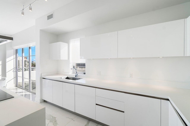 kitchen featuring black electric cooktop, white cabinetry, and sink