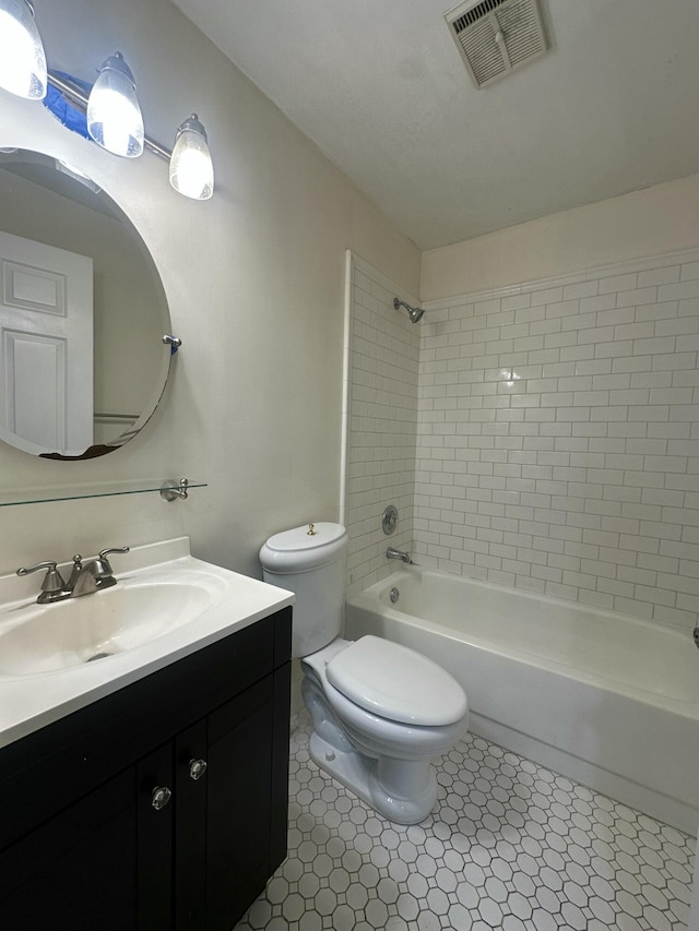 full bathroom featuring tile patterned flooring, tiled shower / bath, vanity, and toilet