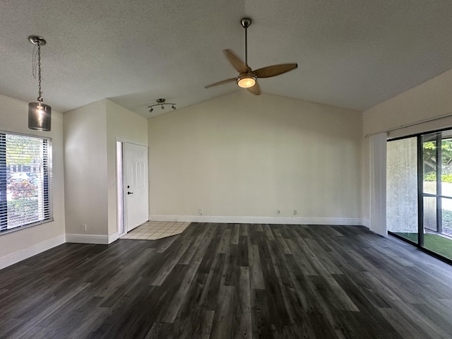 spare room featuring vaulted ceiling, dark hardwood / wood-style floors, a wealth of natural light, and a textured ceiling