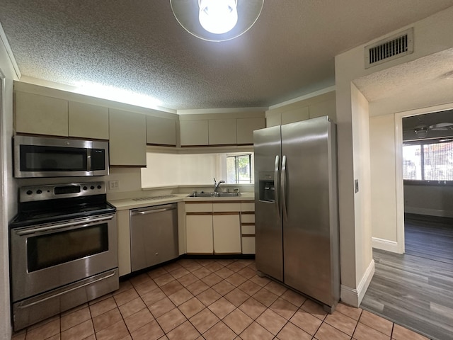 kitchen with light tile patterned flooring, appliances with stainless steel finishes, and a textured ceiling