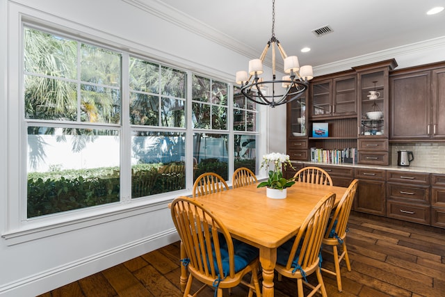 dining room featuring dark wood-type flooring, visible vents, crown molding, and a notable chandelier