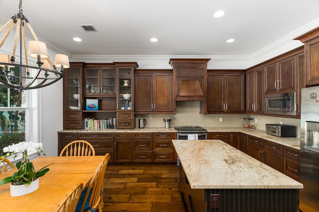 kitchen featuring dark brown cabinetry, stainless steel appliances, hanging light fixtures, light stone countertops, and glass insert cabinets