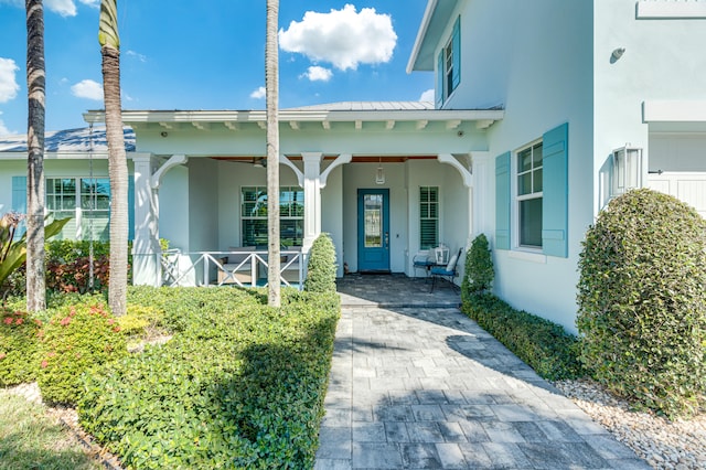 entrance to property with metal roof, a porch, a standing seam roof, and stucco siding