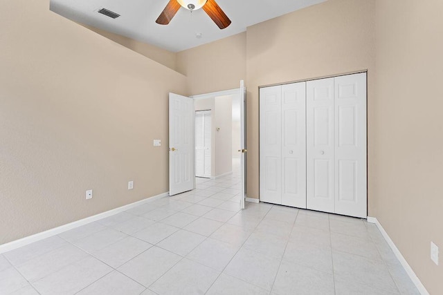 unfurnished bedroom featuring ceiling fan, a closet, a towering ceiling, and light tile patterned floors