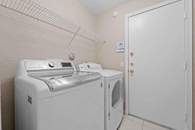 laundry room with light tile patterned flooring, separate washer and dryer, and a textured ceiling