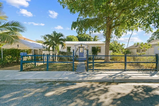 726 N E St, Lake Worth Beach, FL 33460 - view of front of house featuring a fenced front yard, a gate, metal roof, and stucco siding