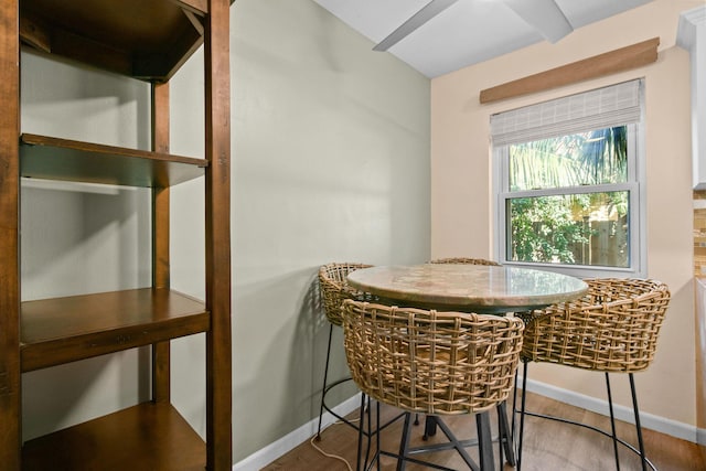 dining area featuring beam ceiling and wood-type flooring