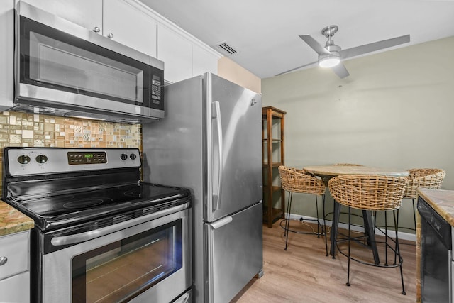 kitchen featuring white cabinetry, ceiling fan, stainless steel appliances, tasteful backsplash, and light wood-type flooring