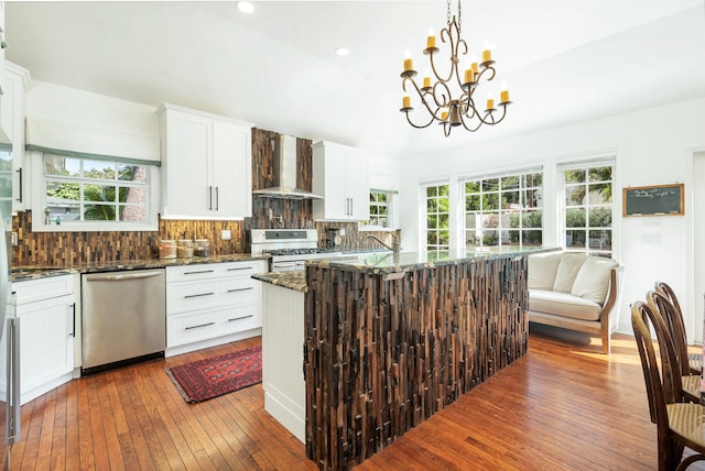 kitchen featuring dark wood-type flooring, wall chimney range hood, stainless steel dishwasher, a wealth of natural light, and white range with gas stovetop