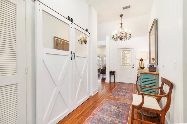 interior space featuring a barn door, dark hardwood / wood-style flooring, and an inviting chandelier