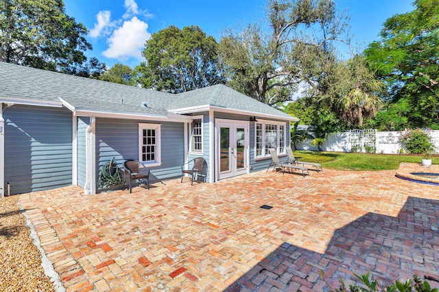 rear view of property featuring a lawn, a patio area, and french doors