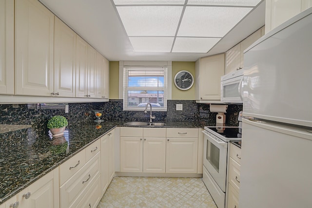 kitchen with decorative backsplash, white appliances, dark stone countertops, and sink