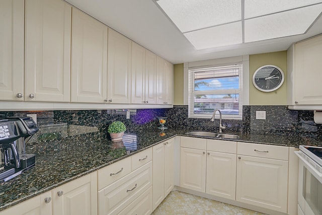 kitchen featuring white range with electric cooktop, sink, dark stone countertops, tasteful backsplash, and white cabinetry