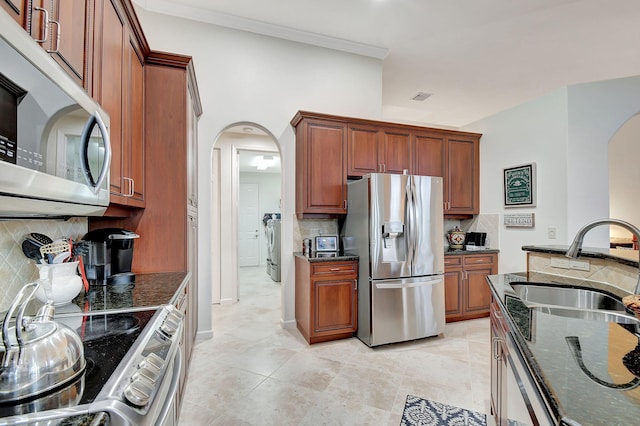 kitchen featuring sink, backsplash, dark stone countertops, appliances with stainless steel finishes, and ornamental molding