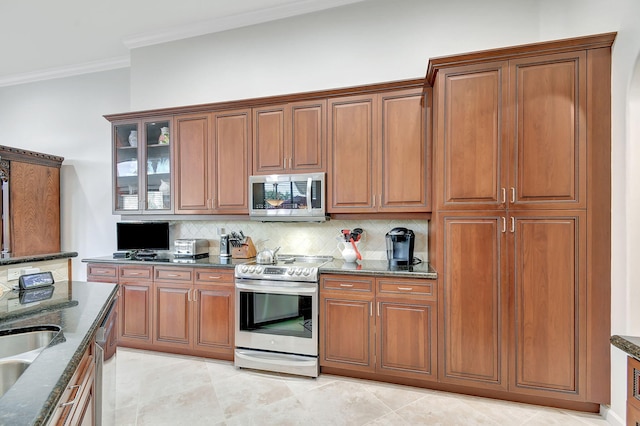 kitchen featuring decorative backsplash, dark stone counters, stainless steel appliances, crown molding, and light tile patterned flooring