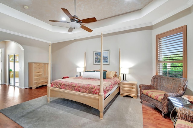 bedroom with hardwood / wood-style floors, a raised ceiling, and ceiling fan