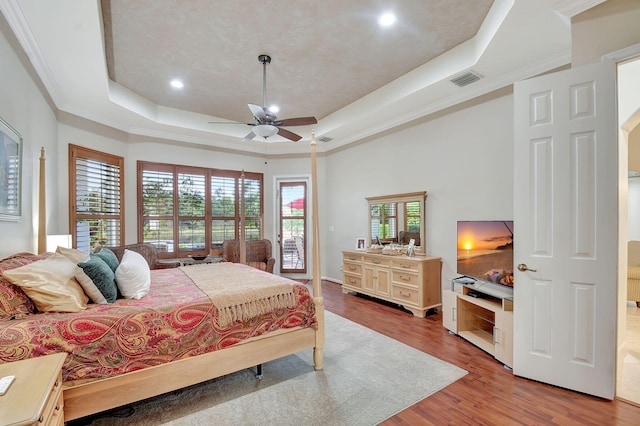 bedroom with a raised ceiling, ceiling fan, crown molding, and hardwood / wood-style flooring