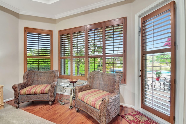 living area featuring a wealth of natural light, ornamental molding, and hardwood / wood-style flooring