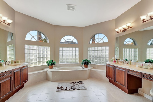 bathroom with tiled tub, tile patterned flooring, vanity, and a healthy amount of sunlight