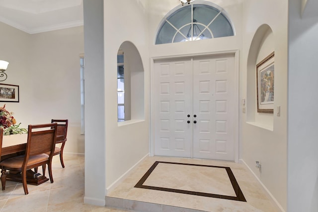 tiled entryway with a towering ceiling and ornamental molding