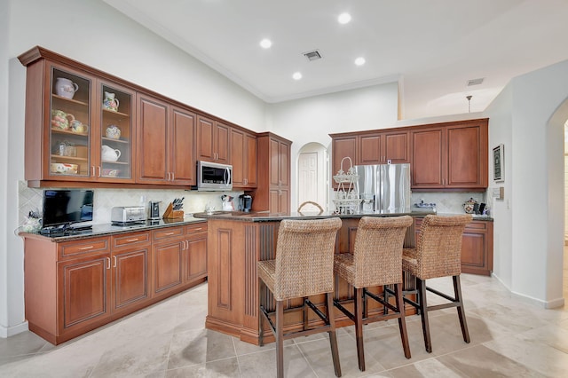 kitchen featuring decorative backsplash, an island with sink, and appliances with stainless steel finishes