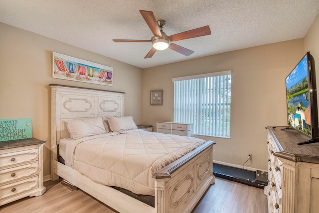 bedroom with ceiling fan, a textured ceiling, and light wood-type flooring