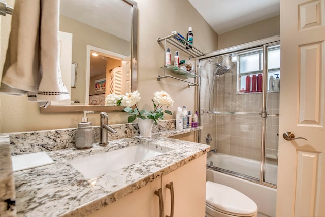 full bathroom featuring vanity, enclosed tub / shower combo, and toilet