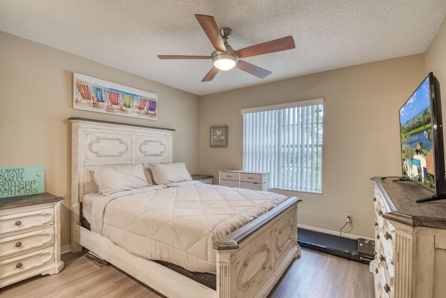 bedroom with light wood-type flooring, a textured ceiling, a ceiling fan, and baseboards