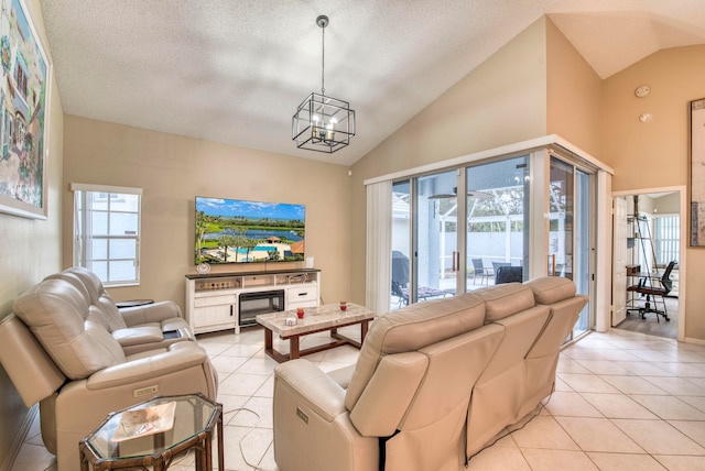 tiled living room featuring a healthy amount of sunlight, a textured ceiling, and an inviting chandelier