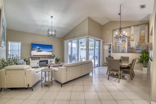 living area with a chandelier, a textured ceiling, light tile patterned floors, and high vaulted ceiling