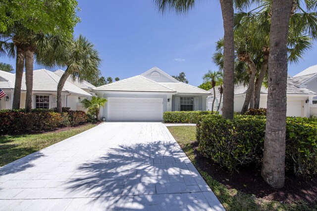 ranch-style home with a garage, decorative driveway, and stucco siding