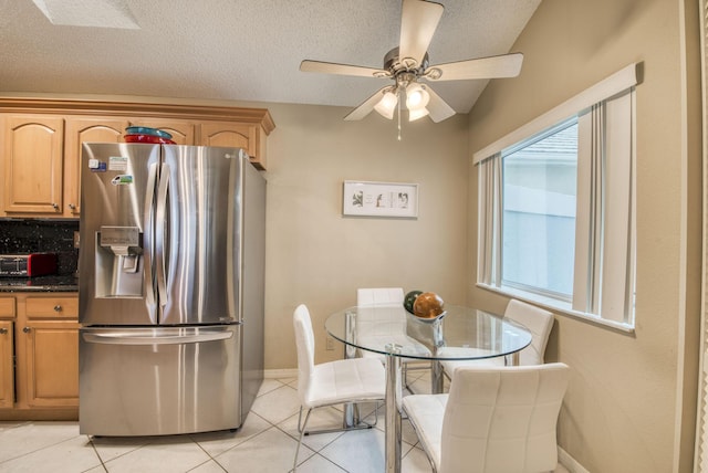 kitchen featuring stainless steel fridge with ice dispenser, ceiling fan, light tile patterned floors, baseboards, and light brown cabinetry