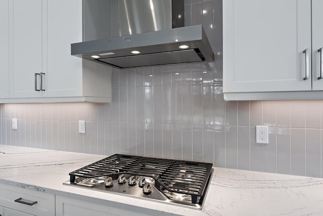 kitchen with backsplash, island range hood, white cabinets, and stainless steel gas stovetop