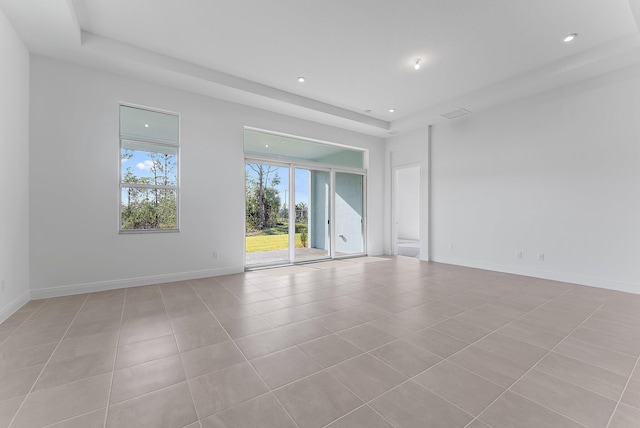 empty room featuring light tile patterned floors and a raised ceiling