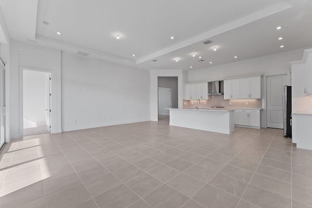 unfurnished living room featuring light tile patterned flooring, a raised ceiling, and sink