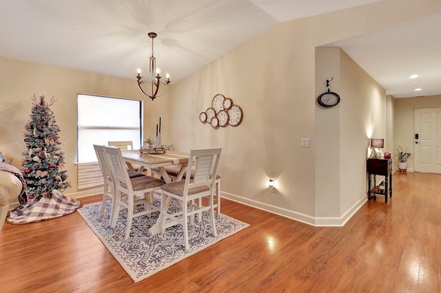 dining room featuring hardwood / wood-style floors, vaulted ceiling, and an inviting chandelier