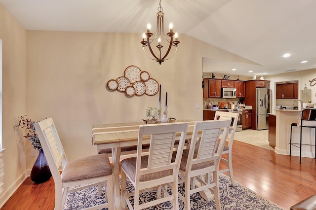 dining area featuring vaulted ceiling, light hardwood / wood-style floors, and an inviting chandelier