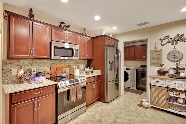 kitchen featuring washer and dryer, appliances with stainless steel finishes, decorative backsplash, and light stone counters