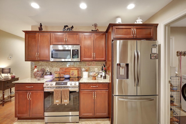 kitchen featuring tasteful backsplash, light stone countertops, stainless steel appliances, and light hardwood / wood-style floors