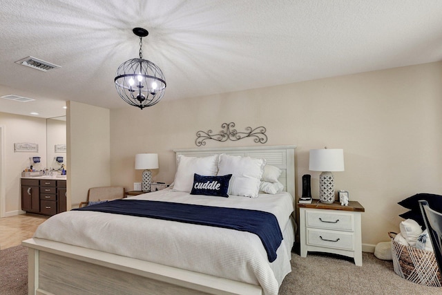 carpeted bedroom featuring a chandelier, a textured ceiling, and ensuite bathroom