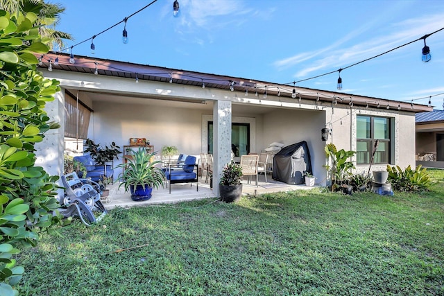 rear view of property featuring an outdoor living space, a patio area, and a lawn