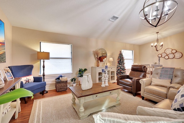 living room with light hardwood / wood-style flooring, a chandelier, and vaulted ceiling