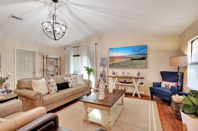 living room with a chandelier, light hardwood / wood-style floors, and vaulted ceiling