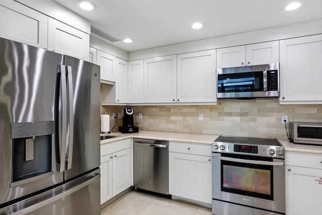 kitchen with white cabinets, backsplash, and stainless steel appliances