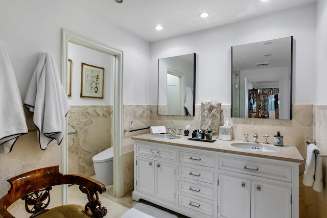 bathroom with vanity, toilet, and tile walls